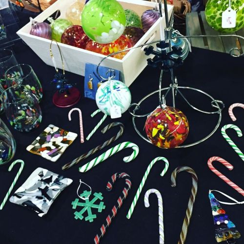 Colorful glass ornaments and candy canes displayed on a black table, with a box of ornaments in the background.