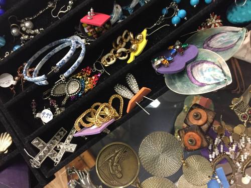 A variety of colorful earrings and jewelry displayed in a black velvet organizer.