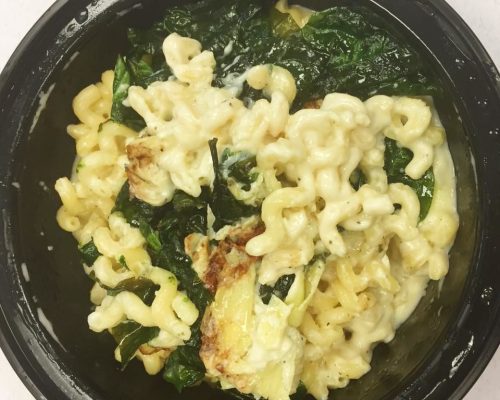 A bowl of creamy macaroni and cheese mixed with spinach and baked until golden brown.