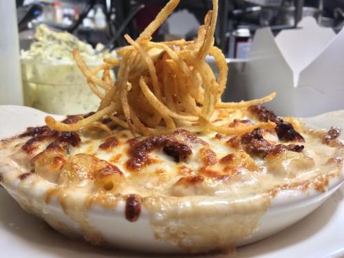 A creamy, cheesy baked dish topped with crispy fried onions, served in a white bowl.