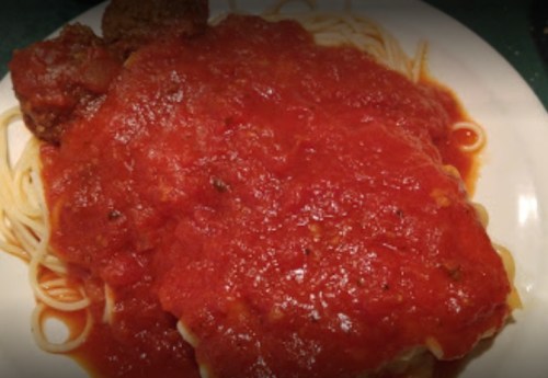 A plate of spaghetti topped with marinara sauce and meatballs.