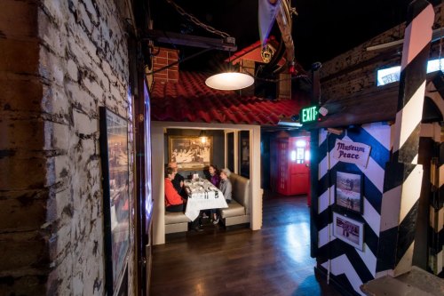 A cozy restaurant interior with a booth, diners at a table, and rustic decor featuring exposed brick and wooden elements.