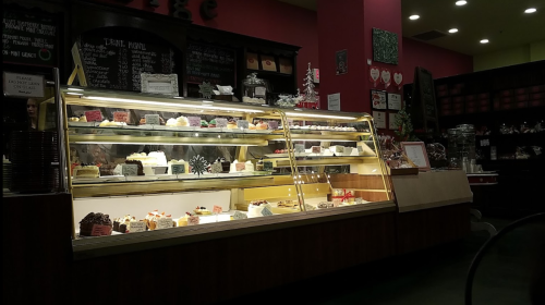A display case filled with various colorful desserts and cakes in a cozy café setting.