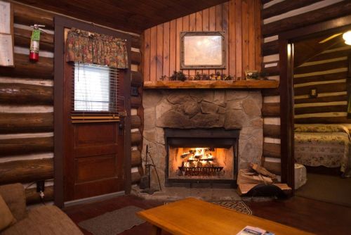 Cozy log cabin interior with a stone fireplace, wooden walls, and a warm, inviting atmosphere.