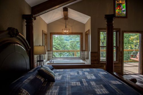 Cozy bedroom with a view, featuring a large window, a tub, and a swing outside, illuminated by natural light.