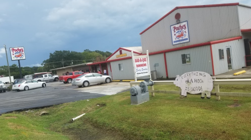 A restaurant with a sign reading "Everything on a hog is good!" and a parking lot filled with cars.