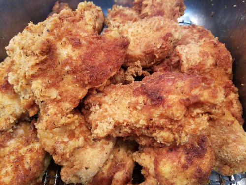 A close-up of golden-brown, crispy fried chicken pieces piled together in a basket.