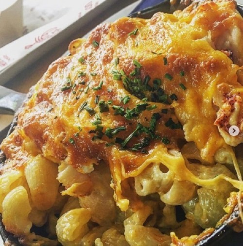 A close-up of cheesy baked macaroni and cheese topped with chives in a cast iron skillet.