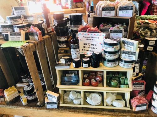 Display of various handmade bath products, including soaps and lotions, with a sign for 20% off (excludes clearance).
