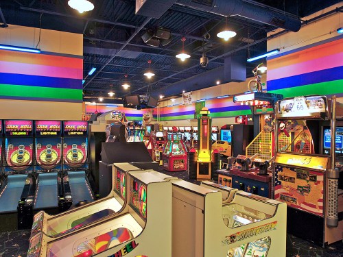 A vibrant arcade filled with various gaming machines and colorful walls, creating a lively atmosphere.