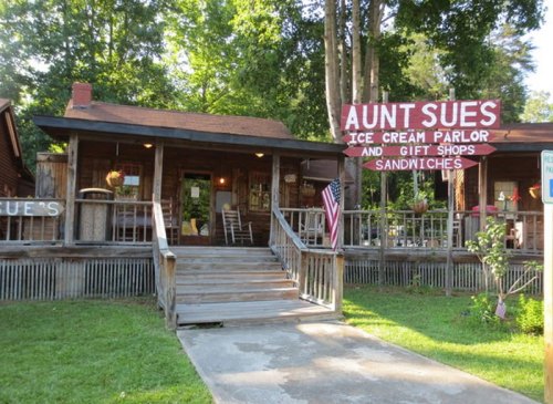 Aunt Sue's Ice Cream Parlor and Gift Shop, featuring a wooden exterior and a welcoming porch surrounded by trees.