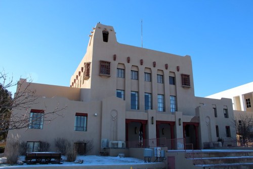 A large adobe-style building with decorative elements, set against a clear blue sky.