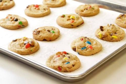 A tray of freshly baked cookies with chocolate chips and colorful candy pieces.