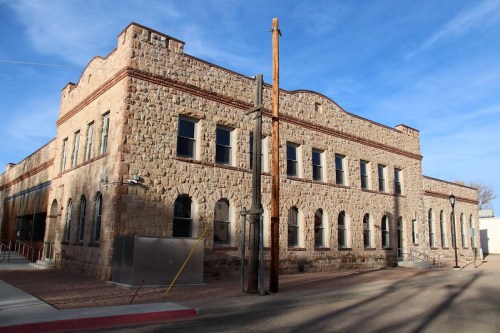 Historic stone building with arched windows and a clear blue sky in the background.