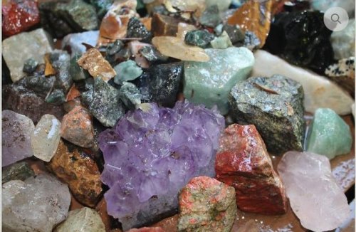 A variety of colorful gemstones and crystals scattered on a surface, showcasing different shapes and textures.
