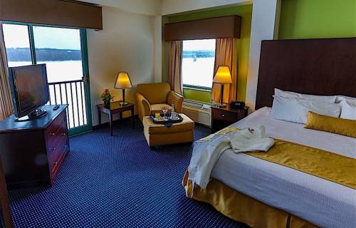 Cozy hotel room with a bed, armchair, TV, and a view of a snowy landscape through large windows.