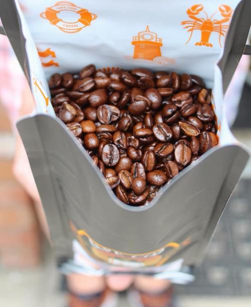 A bag of coffee beans held open, showcasing the rich, dark beans inside.