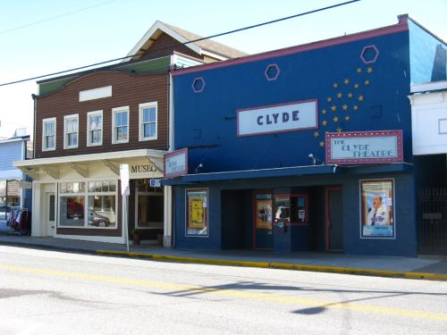 Two buildings side by side: a brown museum and a blue theater with "Clyde" sign and movie posters.
