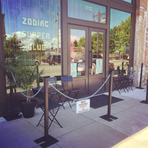 Exterior of Zodiac Supper Club with a sign stating "No Persons Allowed" and empty chairs outside.