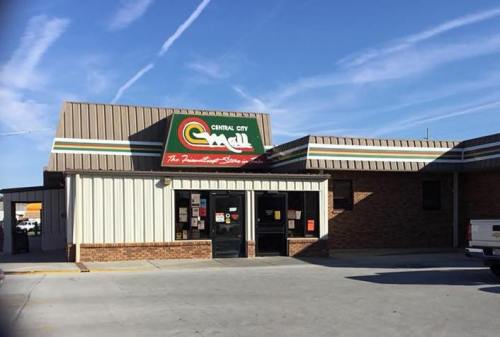A storefront of a convenience store with a colorful sign, featuring a brick facade and a clear blue sky above.