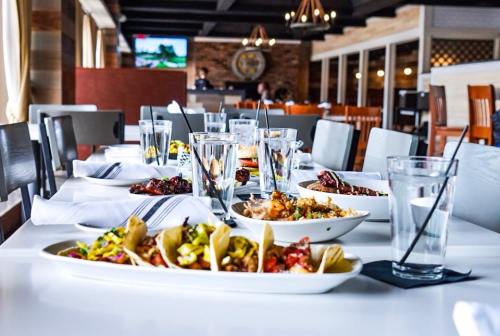 A dining table set with various dishes, including tacos, and glasses of water in a modern restaurant setting.