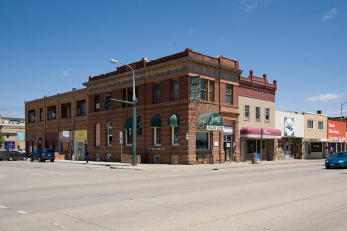 Historic brick buildings at a street corner, featuring shops and a traffic light under a clear blue sky.