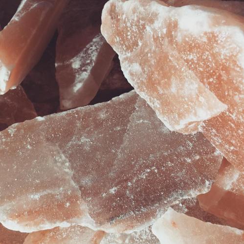 Close-up of large pink salt crystals stacked together, showcasing their rough texture and natural hues.