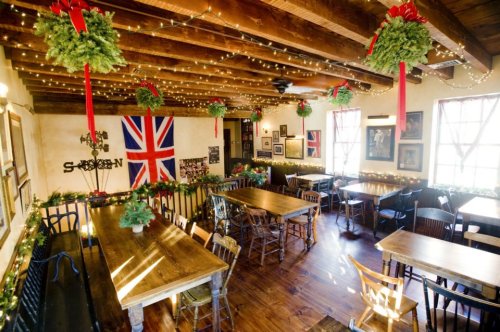 Cozy restaurant interior decorated for the holidays with a British flag, wreaths, and string lights.
