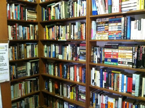 A wooden bookshelf filled with a variety of books in different genres and sizes, creating a colorful display.