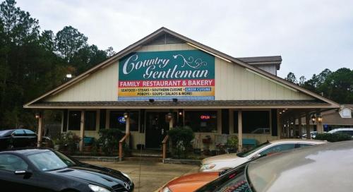 Exterior of Country Gentleman Family Restaurant & Bakery, featuring a colorful sign and surrounded by trees.