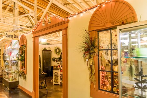 A cozy indoor market with festive decorations, showcasing various shops and holiday lights.