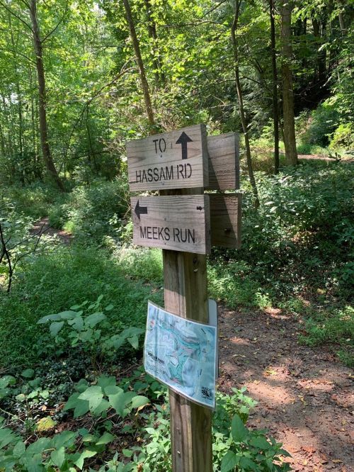Wooden signpost in a forest, pointing to "Hassam Rid" and "Meeks Run," with a map attached below.