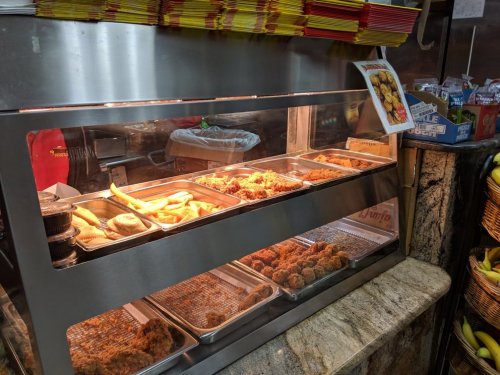A display case filled with various fried foods, including chicken, breadsticks, and sides, in a casual dining setting.