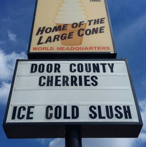 Sign advertising "Door County Cherries" and "Ice Cold Slush" at a location called "Home of the Large Cone."