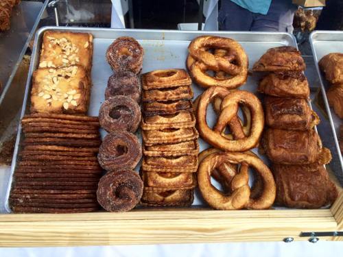 A tray of assorted baked goods, including pastries, pretzels, and cinnamon rolls, arranged neatly.