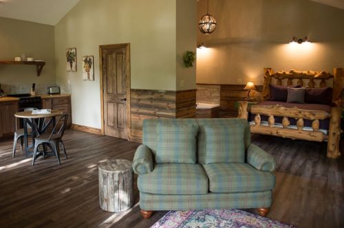 Cozy cabin interior featuring a living area with a sofa, dining table, and a rustic bedroom with a log bed.
