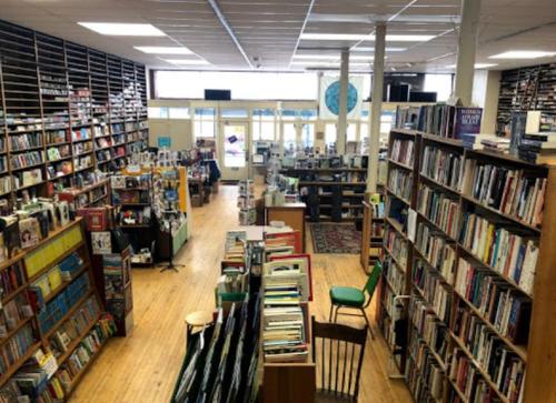 A spacious bookstore with tall shelves filled with books, wooden floors, and a cozy reading area.