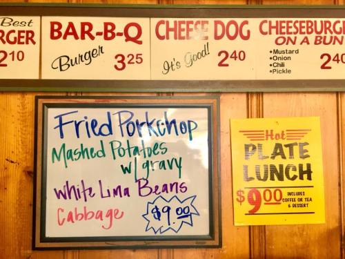 Menu board featuring food items and prices, including fried pork chop, mashed potatoes, and hot plate lunch for $9.00.