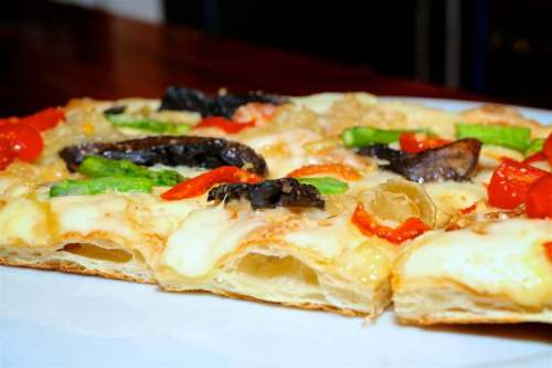 Close-up of a pizza topped with cheese, bell peppers, and mushrooms on a crispy crust.
