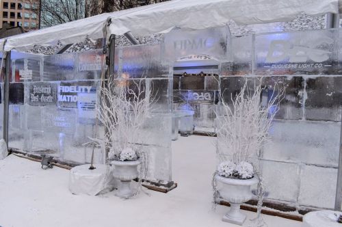 An ice structure with logos, surrounded by white decorations and snow, creating a winter-themed entrance.
