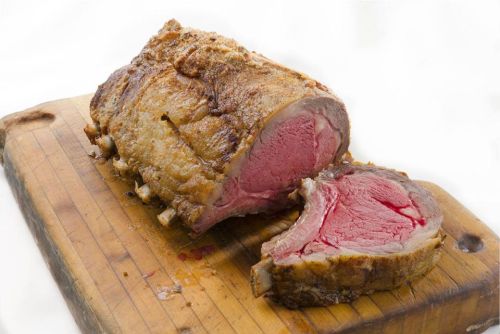 A perfectly cooked roast beef on a wooden cutting board, with a slice cut revealing its pink interior.