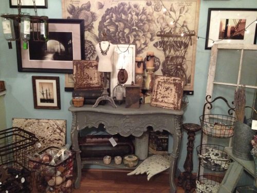 A cozy vintage display featuring a wooden table, framed art, and various decorative items in a charming room.