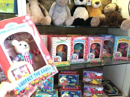 A display of colorful children's toys and games, featuring a bear holding a sign that says "Protect the Earth."