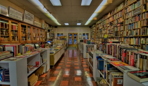 A cozy bookstore aisle lined with shelves of books, leading to a welcoming entrance.