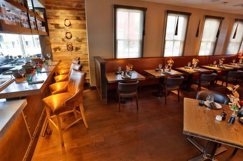 Cozy restaurant interior with wooden accents, tables set for dining, and bar seating illuminated by warm light.