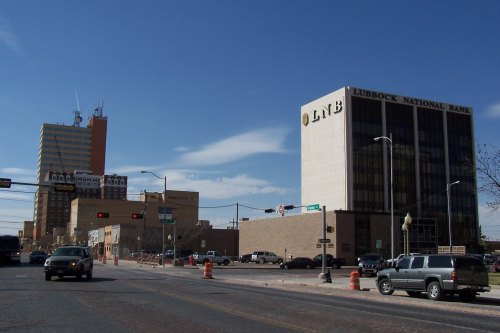Cityscape featuring Lubbock National Bank and surrounding buildings under a clear blue sky, with cars on the road.