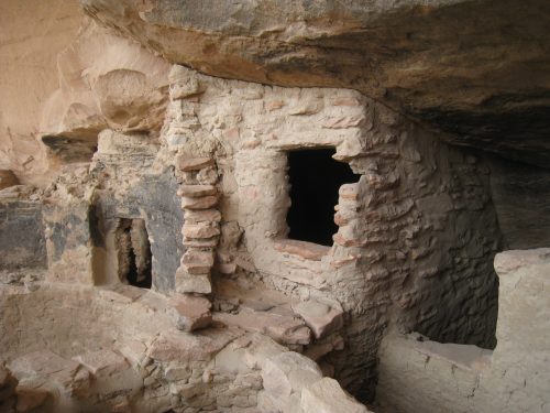 Ancient stone structure with a window, nestled in a rocky cave, showcasing weathered walls and historical architecture.