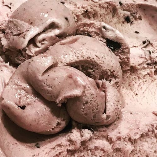 Close-up of creamy pink ice cream with swirls and chocolate flecks, creating a rich, textured appearance.