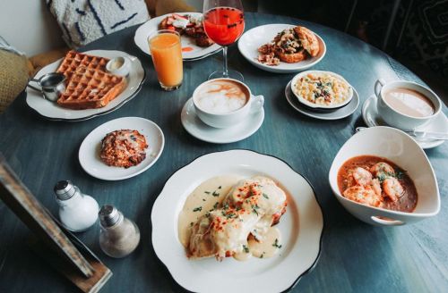 A table spread with various breakfast dishes, including waffles, eggs, coffee, and drinks, all beautifully arranged.