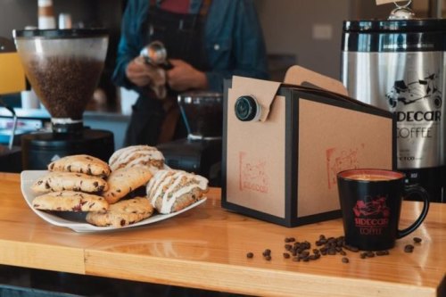 A plate of cookies and a coffee cup on a wooden counter, with a coffee machine in the background.